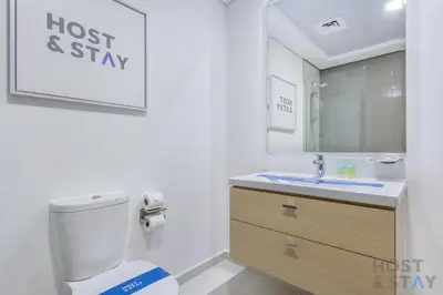 a bathroom with a toilet and a sink and a mirror at Parkview 2BR in Orchid, Damac Hills in Dubai