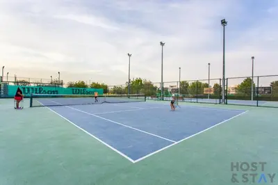 three people playing tennis on a tennis court at Parkview 2BR in Orchid, Damac Hills in Dubai