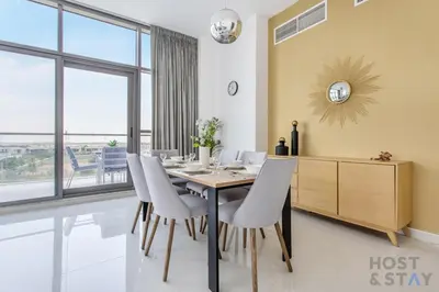 a dining room with a table and chairs at Parkview 2BR in Orchid, Damac Hills in Dubai