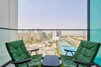 a balcony with two chairs and a view of a city at FAM Living Stylish Studio Apartment in Binghatti Azure JVC in Dubai