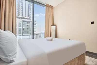 a white bed in a room with a large window at STAY BY LATINEM Luxury 2BR Holiday Home CC 911 Near Burj Khalifa in Dubai