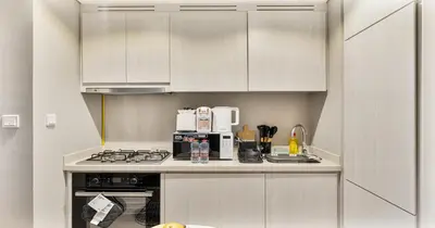 a kitchen with white cabinets and a stove top oven at Savis Homes - Stylish 1 BR near Metro Station in Business Bay in Dubai
