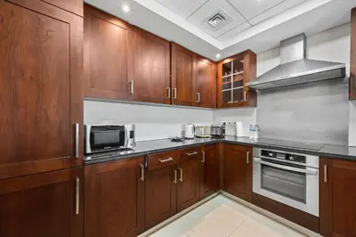 a kitchen with wooden cabinets and a microwave at Breathtaking Burj Khalifa & Fountain Views! in Dubai