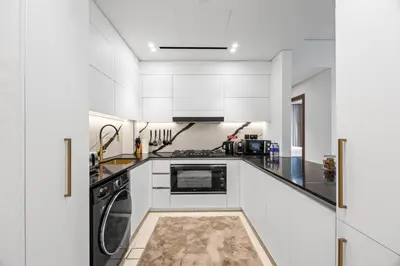 a kitchen with white cabinets and a stove top oven at Trillionaire Residences By Binghatti - Classy 2BR in Dubai