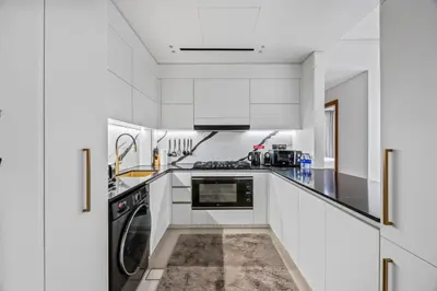 a white kitchen with black appliances and white cabinets at Trillionaire Residences By Binghatti - Classy 2BR in Dubai