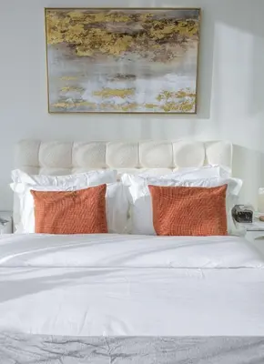 a white bed with orange pillows and a painting above it at Private Pool I Sleeps 6 I Circle Mall in Dubai