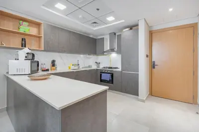 a large kitchen with a white counter and a door at Modern 1BHK Apartment in Pantheon JVC by Czechin in Dubai