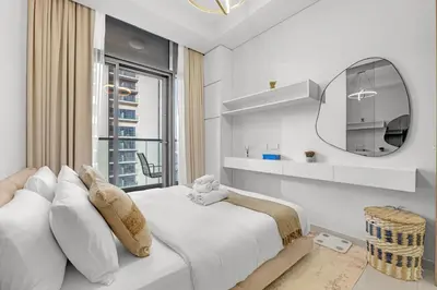 a white bedroom with a large bed and a mirror at Elegant 1 Bedroom Retreat in Business Bay in Dubai