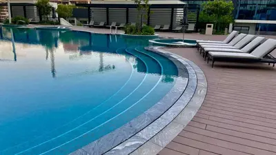 a swimming pool with two lounge chairs next to it at Elegant 1BR with Bedroom Balcony - Sobha Crest C in Dubai