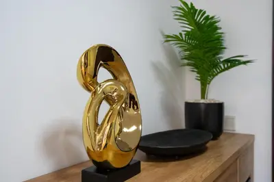 a gold shoe statue on a wooden table with a plant at GlobalStay The Residences Tower 1 Apartments Downtown Dubai in Dubai