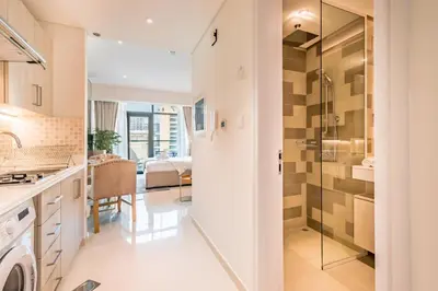 a kitchen and living room with a glass shower door at Upgraded LUX Infinity Pool with Beach Access in Dubai
