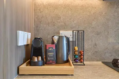 a coffee maker on a wooden shelf in a kitchen at Elegant Apartment near Miracle Garden with Pool & Gym Access in Dubai