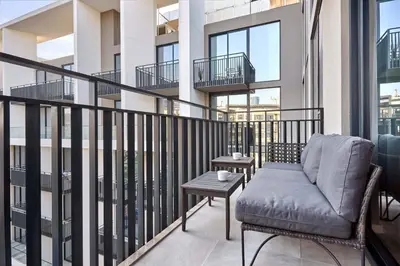 a balcony with a couch and a table at Elegant Apartment near Miracle Garden with Pool & Gym Access in Dubai
