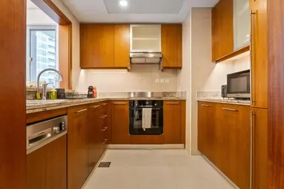 a kitchen with wooden cabinets and a sink and a microwave at Boema Apartments - Terrace with Stunning Burj View in Dubai