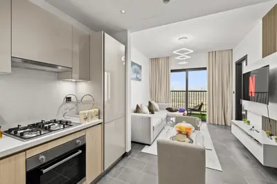 a kitchen and living room with a stove and a couch at Premium Stay in Sobha 1BR with Extra Room and Balcony in Dubai