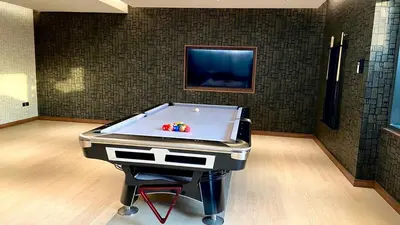 a pool table in a room with a flat screen tv at Premium Stay in Sobha 1BR with Extra Room and Balcony in Dubai