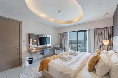 a white bedroom with a large bed and a desk at Stylish Stay - 1 Bedroom - High Floor in Dubai