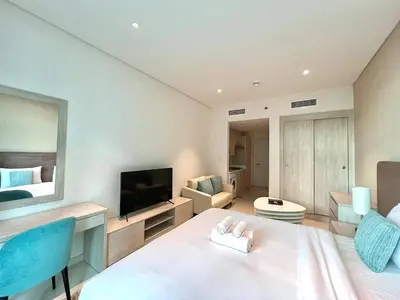 a room with a bed and a tv and a couch at LUX Infinity Pool with GYM, Private Beach Studio in Dubai