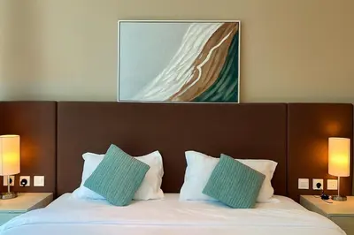 a bed with two pillows and a painting above it at LUX Infinity Pool, Gym, Beach, Parking Studio in Dubai
