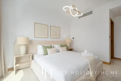a white bedroom with a large bed and a lamp at LUX The Vida Marina Residence in Dubai