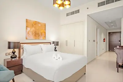 a bedroom with a large white bed with two towels on it at FIRST CLASS Studio Cozy Elegance in Dubai
