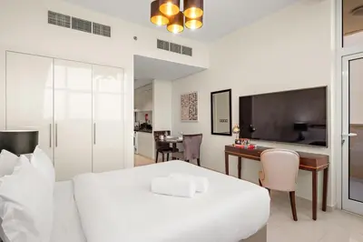 a bedroom with a bed and a desk and a television at FIRST CLASS Studio Cozy Elegance in Dubai