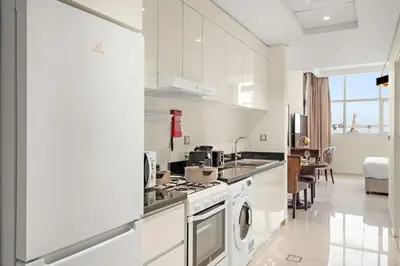 a white kitchen with a stove and a dishwasher at FIRST CLASS Studio Cozy Elegance in Dubai