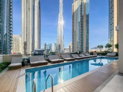a swimming pool with lounge chairs and a city skyline at Act One Luxury 2BR Front-Row Burj & Fountain Views in Dubai