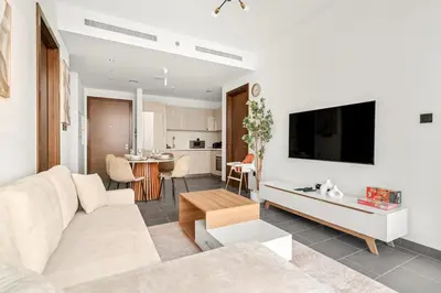 a living room with a couch and a tv on a wall at FIRST CLASS 2BR Bright and Elegant Living in Dubai