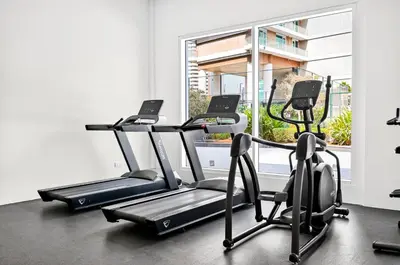 a gym with three exercise bikes and a window at Sylish Studio with Balcony Views Near Dubai Mall in Dubai