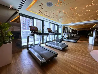 a gym with several treadmills and a row of windows at Your Hollywood-Style Hideaway -DAMAC Paramount in Dubai