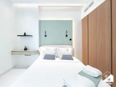 a bedroom with a large white bed with white sheets at Luxury 1BR Escape, Resort-Style Living in Dubai in Dubai