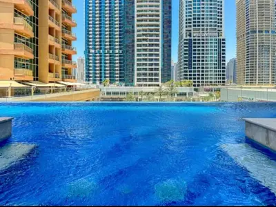 a large pool of blue water with tall buildings at Modern 1BR with city views large space in Dubai