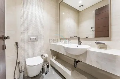 a bathroom with a white sink and a toilet at Spacious High-Floor 2BR with Stunning City and Burj Khalifa Views, Quick Drive to Downtown, and Steps from the Bus Station, Nobles, Business Bay by Deluxe Holiday Homes in Dubai