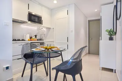 a kitchen and dining room with a glass table and chairs at Stylish 1BR Apartment, ZADA Tower with Pool & Gym, Business Bay in Dubai