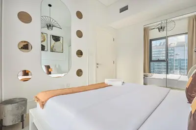 a white bedroom with a large bed and a mirror at Stylish 1BR Apartment, ZADA Tower with Pool & Gym, Business Bay in Dubai