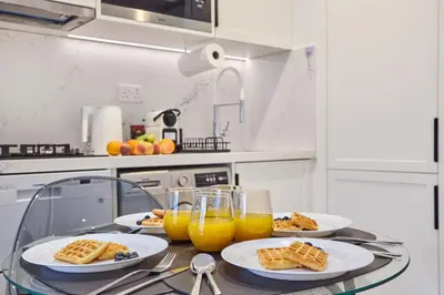 a table with plates of food and glasses of orange juice at Stylish 1BR Apartment, ZADA Tower with Pool & Gym, Business Bay in Dubai