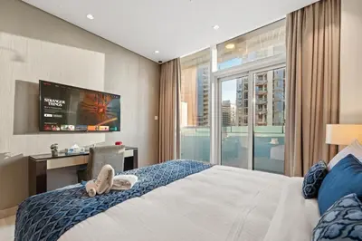 a bedroom with a bed with a tv and a window at DAMAC MAISON DISTINCTION - Burj Khalifa View, Fee Parking in Dubai