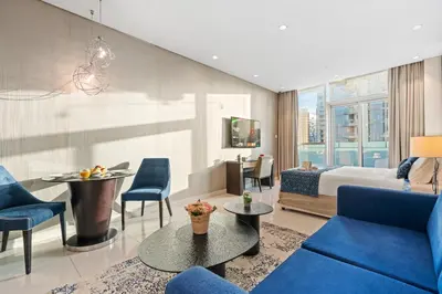 a hotel room with a bed and blue chairs at DAMAC MAISON DISTINCTION - Burj Khalifa View, Fee Parking in Dubai