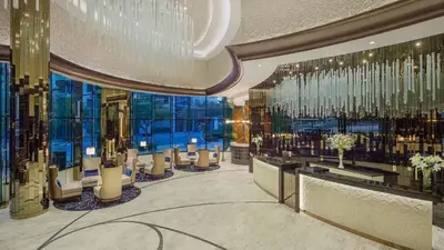 a hotel lobby with a chandelier and tables and windows at DAMAC MAISON DISTINCTION - Burj Khalifa View, Fee Parking in Dubai