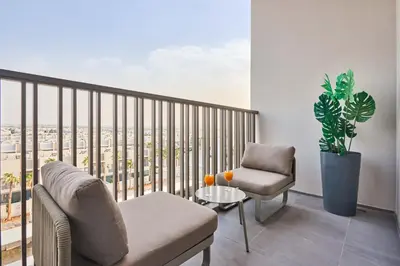 a living room with a balcony with a couch and a chair at New Studio Apartment, MAG 910 - Dubai Stay in Dubai