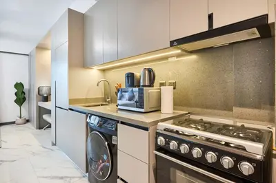 a kitchen with a stove and a washer and dryer at New Studio Apartment, MAG 910 - Dubai Stay in Dubai
