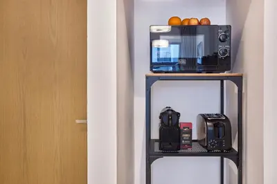 a microwave and a toaster oven on a shelf at Le Pont Apartment in Port de La Mer with Pool Access, Retreat near the Beach in Dubai