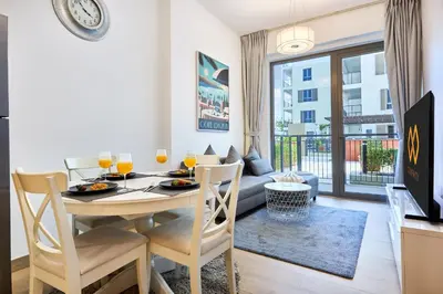 a dining room with a table and chairs and a couch at Le Pont Apartment in Port de La Mer with Pool Access, Retreat near the Beach in Dubai