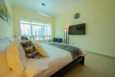 a bedroom with a bed with pillows and a tv at Metrofront Stay - Walk to Iconic Dubai Spots in Dubai