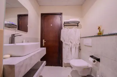 a bathroom with a sink and a toilet and a wooden door at Metrofront Stay - Walk to Iconic Dubai Spots in Dubai