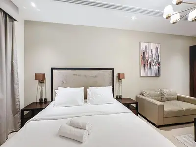 a white bedroom with a large bed and a couch at Stylish Studio in Elite Downtown in Dubai