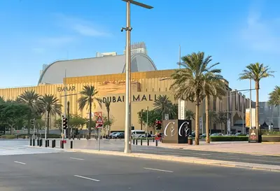 a large building with palm trees in front of a street at Luxury 1BR with Workspace Next To Dubai Mall in Dubai