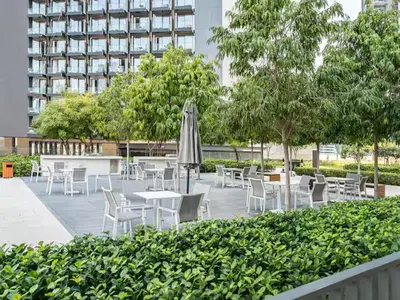 a patio with tables and chairs and an umbrella at Luxury 2BR- Pool with Burj View- 5 Min to Dubai Mall in Dubai