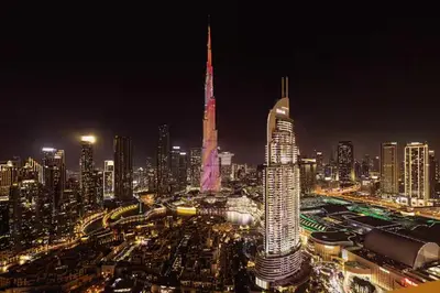 a lit up city at night with a tall building at Luxury 2BR- Pool with Burj View- 5 Min to Dubai Mall in Dubai